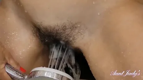 Une femme au foyer sexy, au pubis poilu, se masturbe en toute intimité sous la douche.